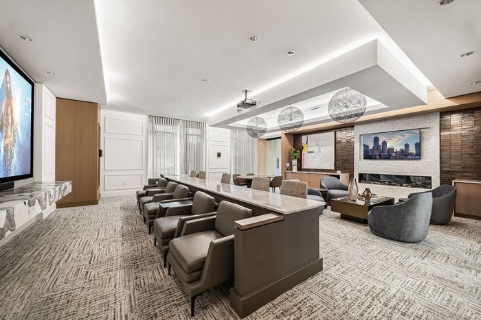 Luxurious conference room with elegant seating, a marble-topped table, modern ceiling lights, and a large flat-screen TV.