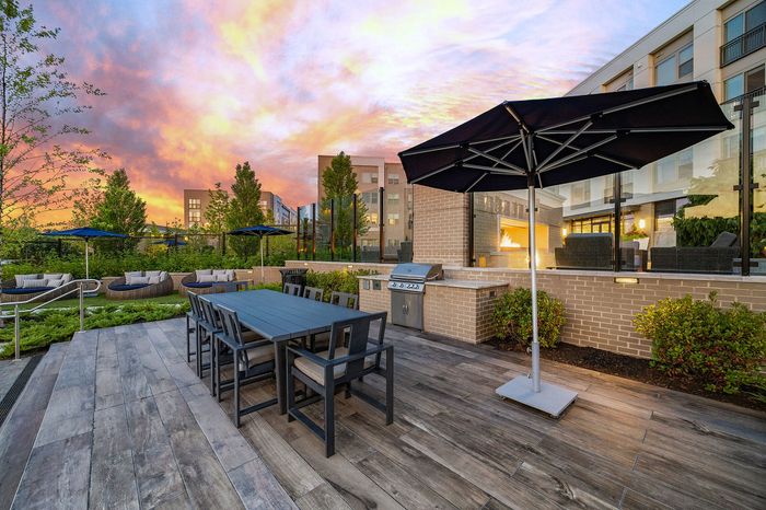 Luxurious outdoor terrace with elegant dining set, modern grill station, and ambient lighting against a stunning sunset backdrop.