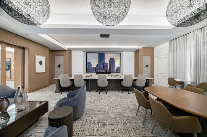 Sophisticated conference room with stylish decor, featuring modern lighting, plush seating, and a large backdrop screen for presentations.