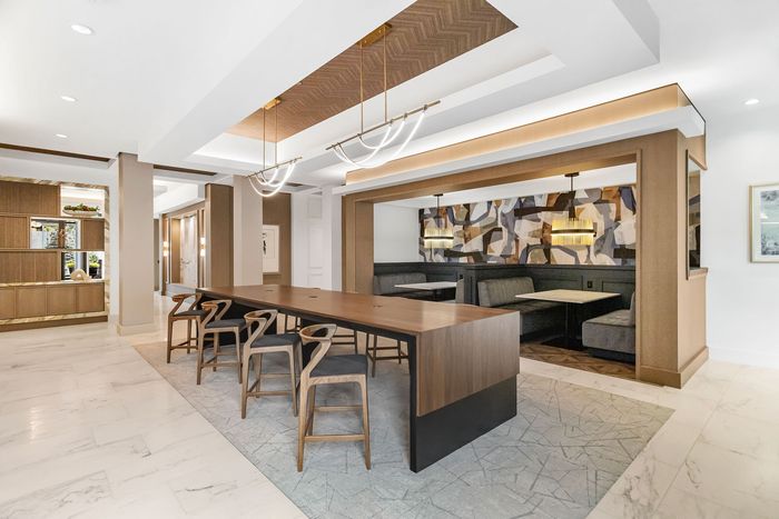 Sophisticated lounge area with modern wooden table, elegant chairs, and plush booth seating against an artistic backdrop.