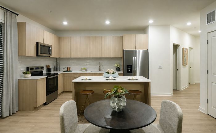 Modern kitchen with sleek wooden cabinetry, stainless steel appliances, and a cozy dining area.