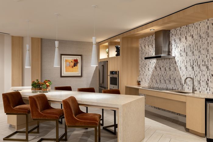 Elegant modern kitchen with sleek marble island, plush brown chairs, and stylish pendant lighting creating a warm, inviting atmosphere.