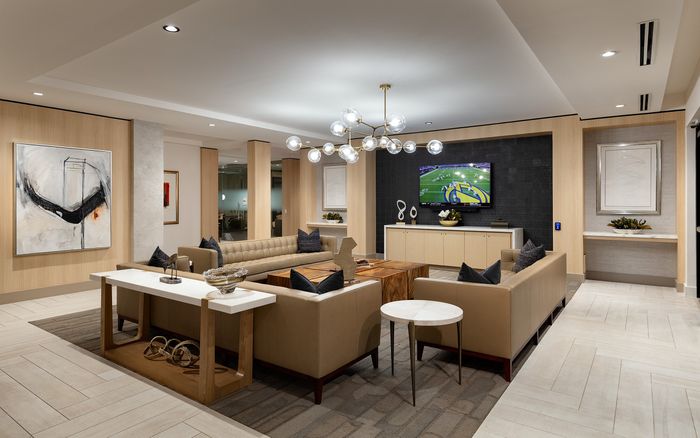 Sophisticated living room with modern decor, plush leather sofas, abstract art, and a sleek flat-screen TV.