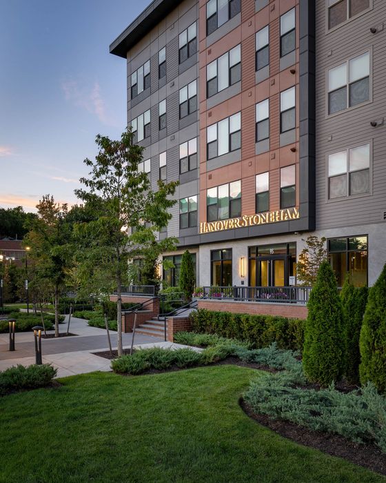 Modern multi-story apartment building with lush landscaping and inviting entrance at dusk.
