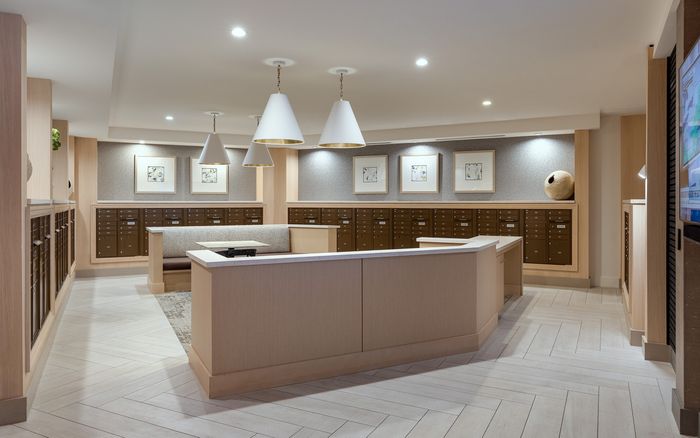 Elegant lobby mailroom with modern lighting, warm wood tones, and sleek mailbox design for a sophisticated apartment experience.