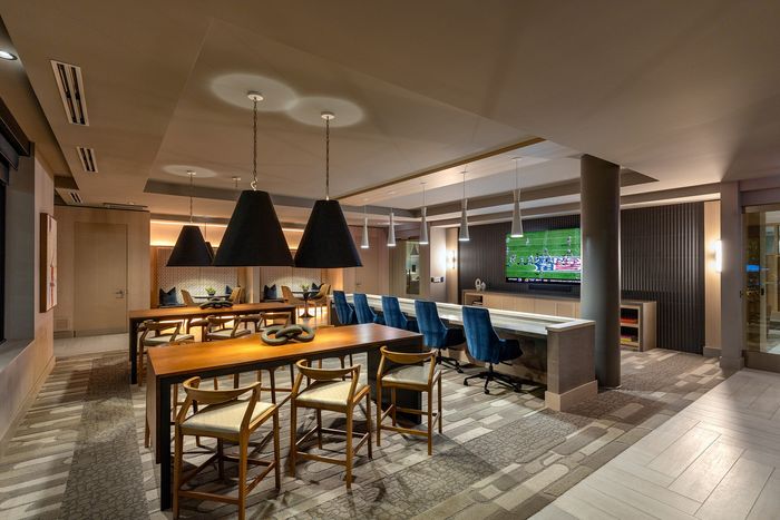 Luxurious interior featuring a sleek dining area with wooden tables, stylish blue chairs, and modern pendant lighting, perfect for entertaining in style.