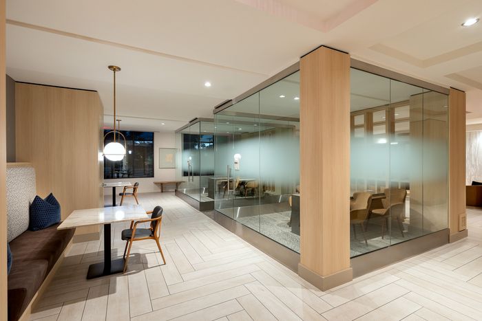 Modern, elegant workspace with glass walls, cozy seating area, and stylish lighting.