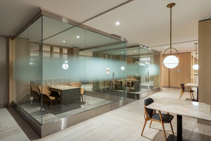 Elegant office space with glass-walled meeting rooms featuring modern decor and cozy seating.
