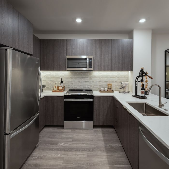 Contemporary kitchen with sleek stainless steel appliances, elegant dark wood cabinets, and a stylish backsplash creating a sophisticated cooking space.