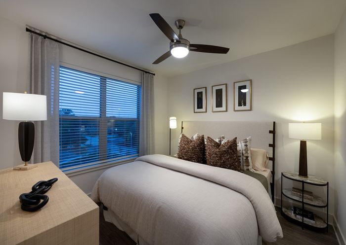 Inviting bedroom with elegant decor, showcasing a cozy bed, stylish lighting, and large windows for natural light.