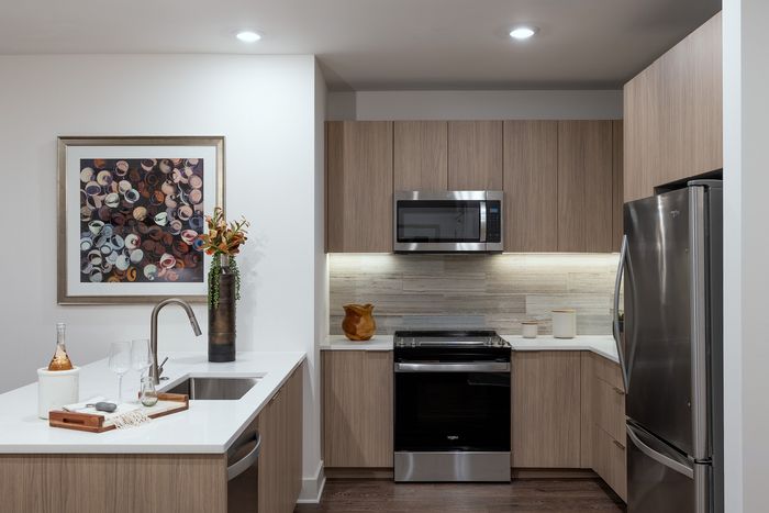 Sleek modern kitchen with stylish wood cabinetry, stainless steel appliances, and an elegant white countertop, perfect for entertaining.