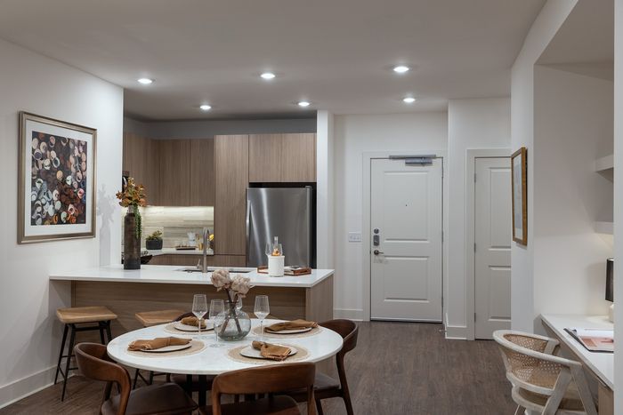 Elegant open-concept kitchen with modern wood cabinetry, stainless steel appliances, and a cozy dining area, ideal for entertaining.