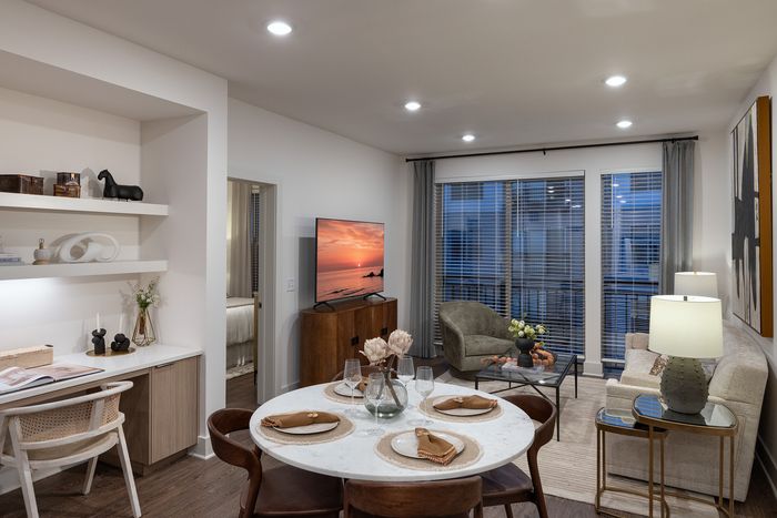 Chic and modern living room with open dining area, cozy seating, stylish decor, and large windows for natural light.