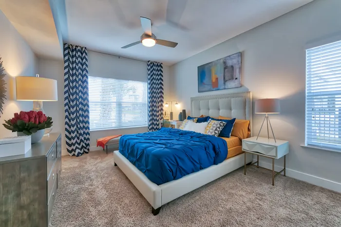 The Reserve at Vero Beach, interior, spacious bedroom, ceiling fan, carpet, bed, dresser, 2 large windows