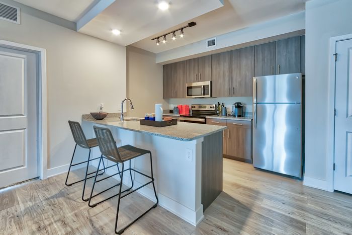 The Reserve at Vero Beach, interior, open concept, kitchen, wood floors, stainless steel appliances, refrigerator, microwave, stove/oven, breakfast bar counter, dark cabinets