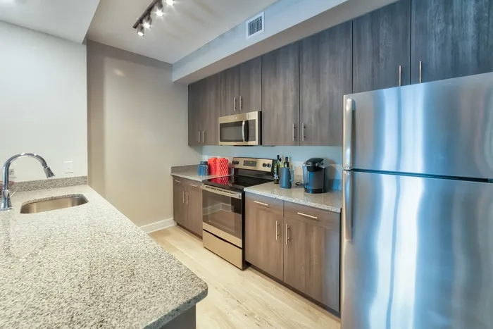 The Reserve at Vero Beach, interior, kitchen, wood floors, stainless steel appliances, refrigerator, microwave, stove/oven, breakfast bar counter, dark cabinets