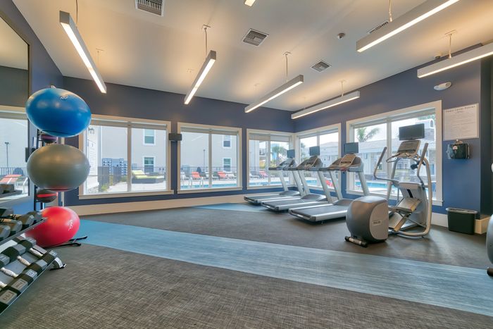 The Reserve at Vero Beach, interior, fitness center, treadmills, large windows, view of pool, hand weights, elliptical