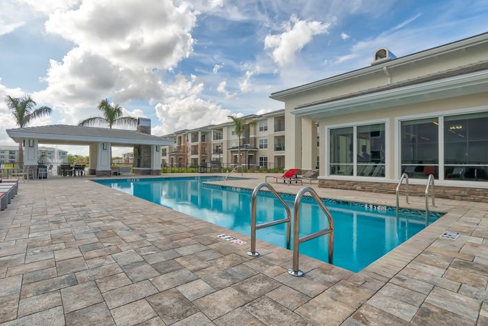 The Reserve at Vero Beach, exterior, sparkling blue pool, clubhouse, pavilion, lounge chairs, palm trees