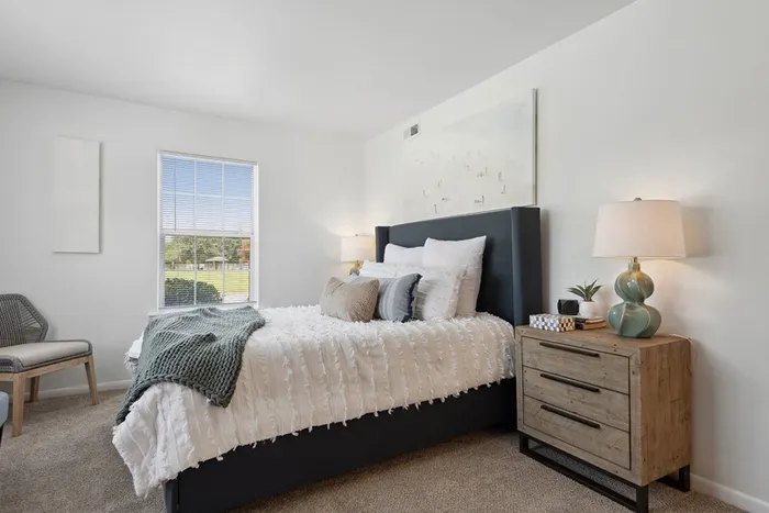 ReNew Virginia Beach bedroom with upholstered headboard and view of lush greenery