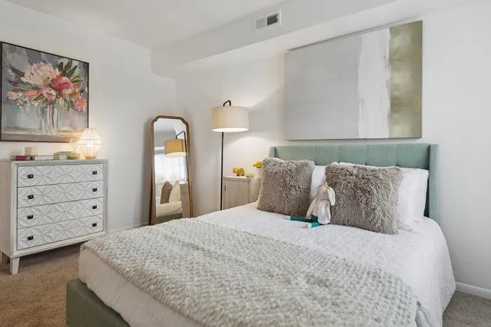 Bedroom at ReNew Virginia Beach showcasing plush bed, full length mirror, and dresser
