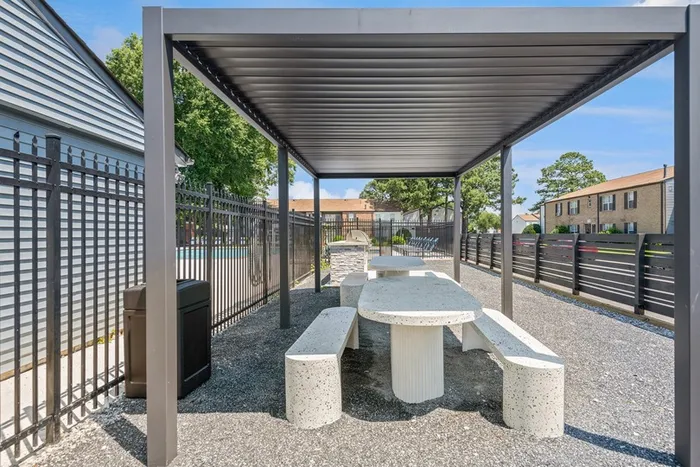 Picnic tables under a pergola next to the pool at ReNew Virginia Beach