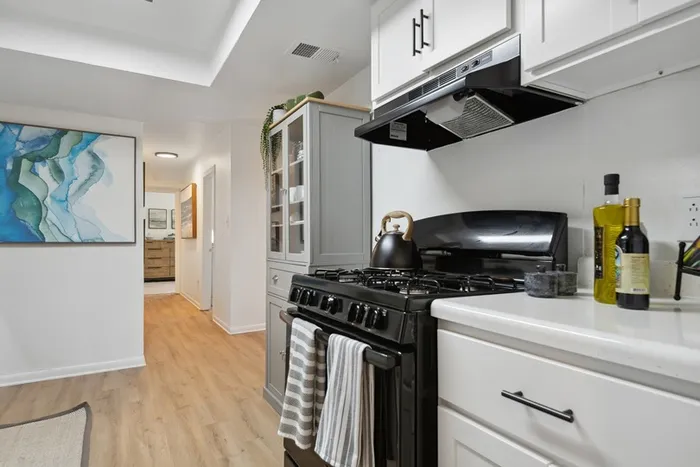 Renovated kitchen at ReNew Virginia Beach with white cabinetry and black appliances