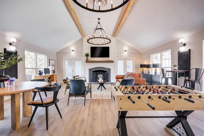 Bright and stylish open-concept living space with modern furnishings, foosball table, and elegant lighting.