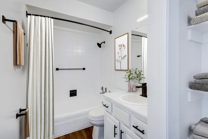 Stylish bathroom at ReNew on Cantrell with a white bathtub, modern sink, and decorative floral artwork.