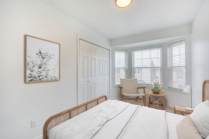 Inviting bedroom at ReNew on Cantrell with natural light, featuring a comfortable bed, closet, and soft-toned decor.