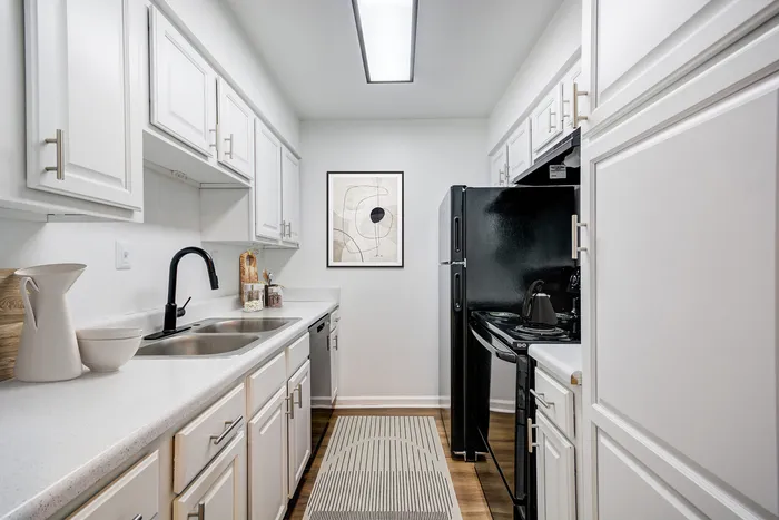 Contemporary kitchen at ReNew on Cantrell with white cabinetry, black appliances, and elegant countertops.