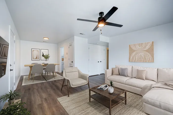 Inviting living room at ReNew on Cantrell with modern decor, featuring a beige sofa, elegant coffee table, and adjoining dining area.