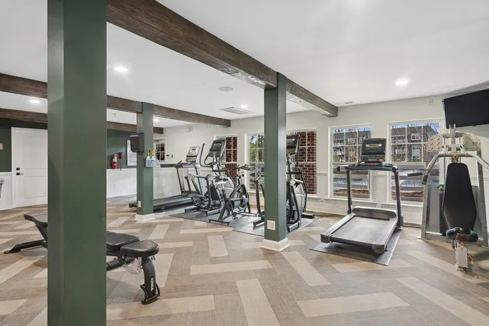 Modern fitness center with cardio machines, weight bench, and sleek wood accents.