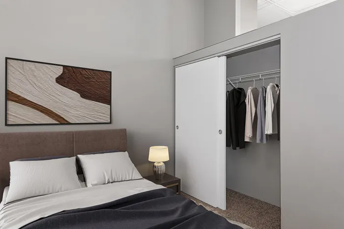 Elegant bedroom with a plush bed, stylish art, and a neatly organized open closet.