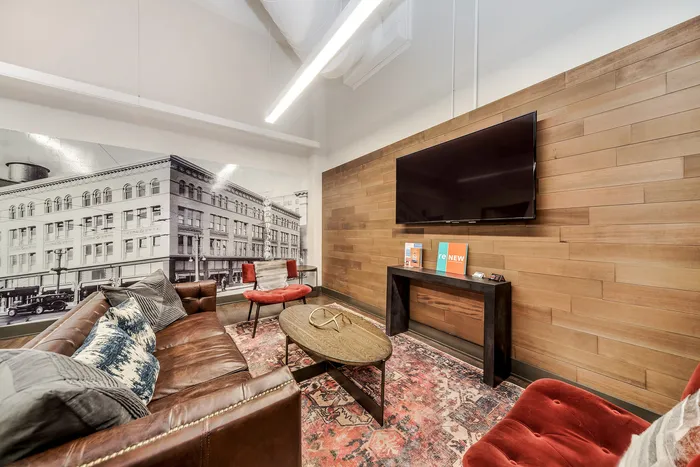 Stylish lounge area with leather sofa, vintage city mural, and modern decor.