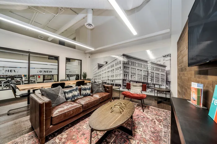 Modern lounge space with a leather sofa, designer lighting, and a vintage cityscape mural.
