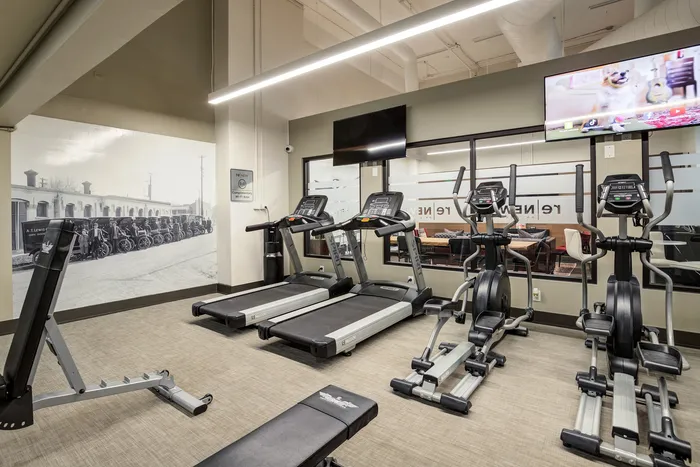 Contemporary fitness center with treadmills, ellipticals, and wall art, offering a motivating workout space.