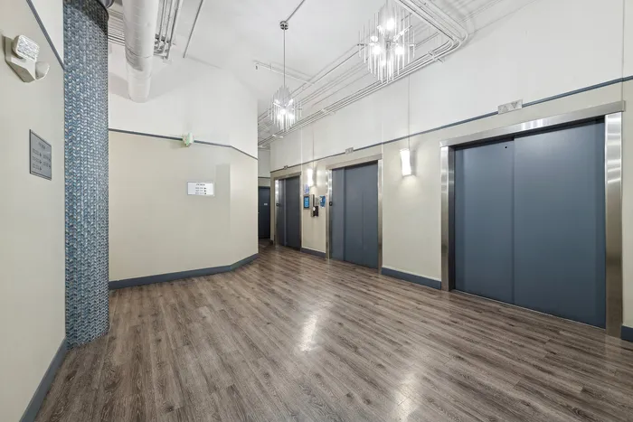 Stylish lobby featuring modern elevators with sleek wooden flooring and contemporary lighting.