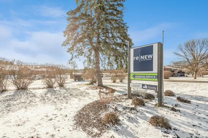 Scenic winter view of ReNew at The Greens leasing office sign with snow-covered landscape.