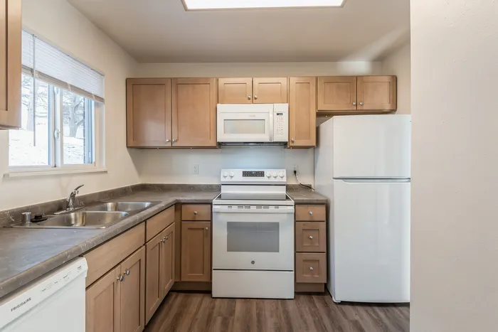 Modern kitchen with wooden cabinets, stainless steel sink, and sleek appliances.
