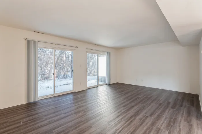 Bright living room with large glass doors, wooden flooring, and a serene snowy view.