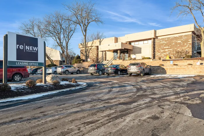 Exterior view of the ReNew High Ridge leasing office featuring modern architecture and a parking lot.