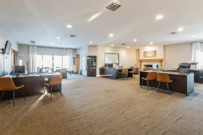 Inviting and modern office space with multiple desks, natural light, and a cozy fireplace.