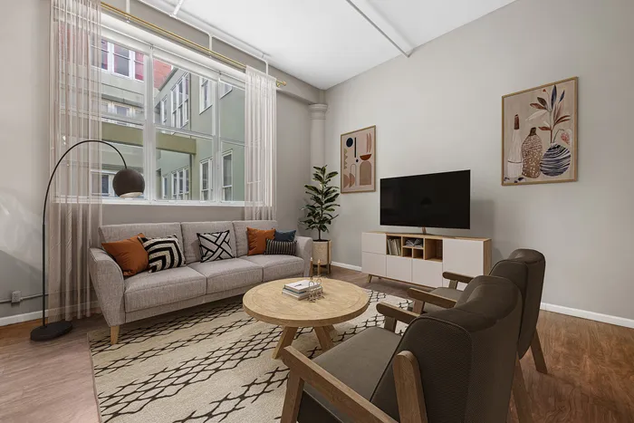 Stylish living room with modern decor, a cozy sofa, elegant armchairs, large window view, and a sleek TV setup.