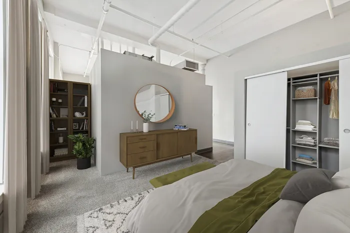 Contemporary bedroom with a wooden dresser, round mirror, built-in closet, and chic decor elements.