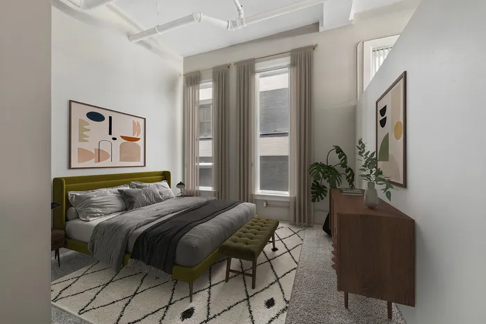 Contemporary bedroom with chic decor, featuring a plush green bed, abstract art, and ample natural light.