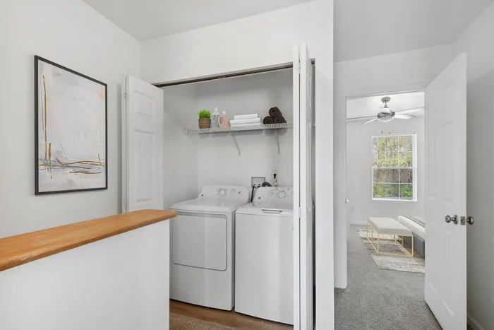 Bright laundry nook with modern washer and dryer, adjacent to a cozy bedroom.
