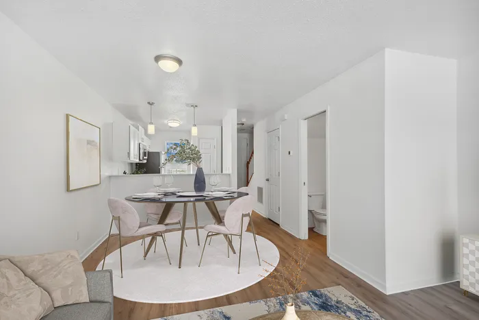 Elegant modern living space featuring a round dining table with four chairs, a cozy seating area, and a view of a contemporary kitchen.