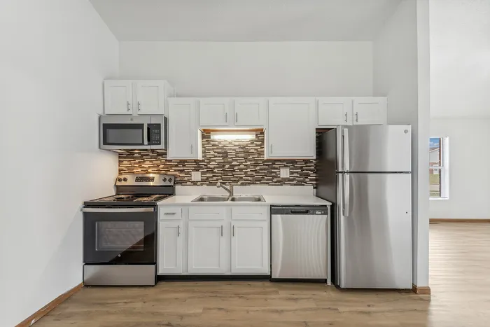 Contemporary kitchen with stainless steel appliances and white cabinetry.