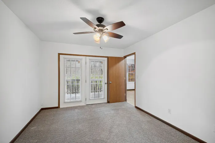 Bright bedroom with carpeted flooring, a ceiling fan, and French doors leading outside.