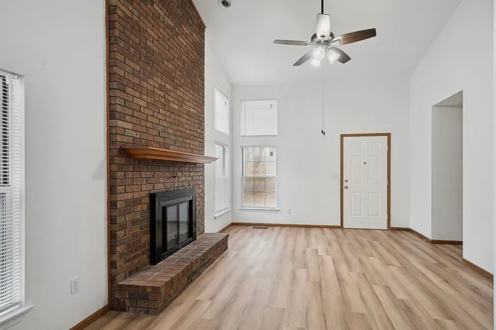 Inviting living room featuring a rustic brick fireplace, vaulted ceilings, and abundant natural light.